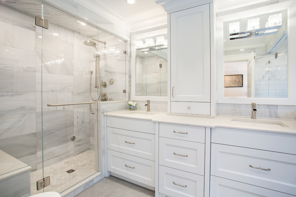 Inspiration for a mid-sized transitional master bathroom in Vancouver with shaker cabinets, grey cabinets, a drop-in tub, an alcove shower, a wall-mount toilet, gray tile, marble, grey walls, porcelain floors, a drop-in sink, engineered quartz benchtops, grey floor, a hinged shower door and white benchtops.