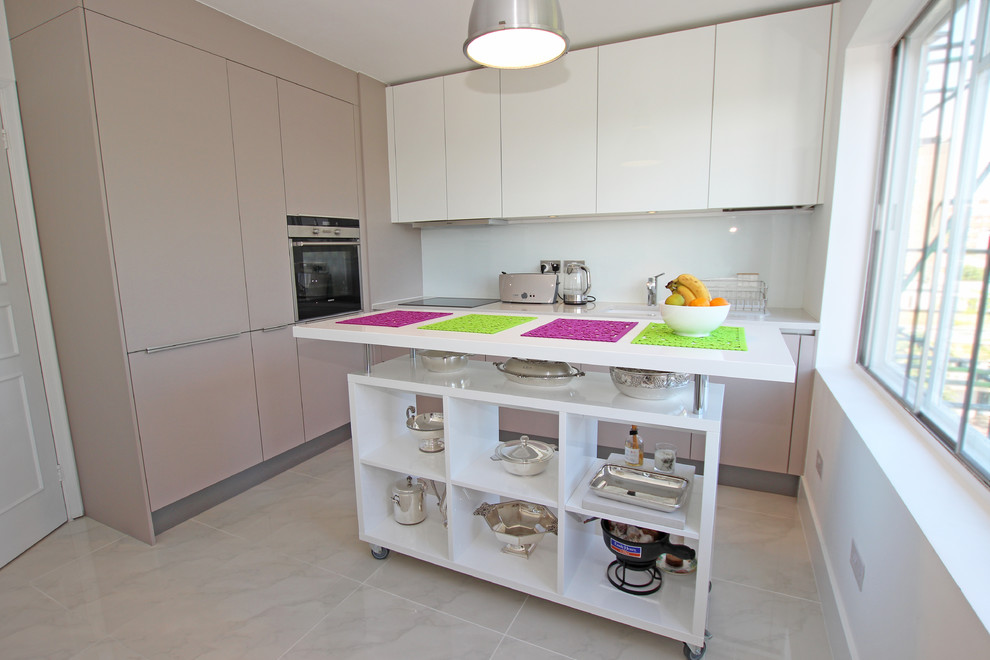 This is an example of a small modern l-shaped separate kitchen in London with with island, an undermount sink, flat-panel cabinets, white cabinets, white splashback, glass sheet splashback, panelled appliances and marble floors.
