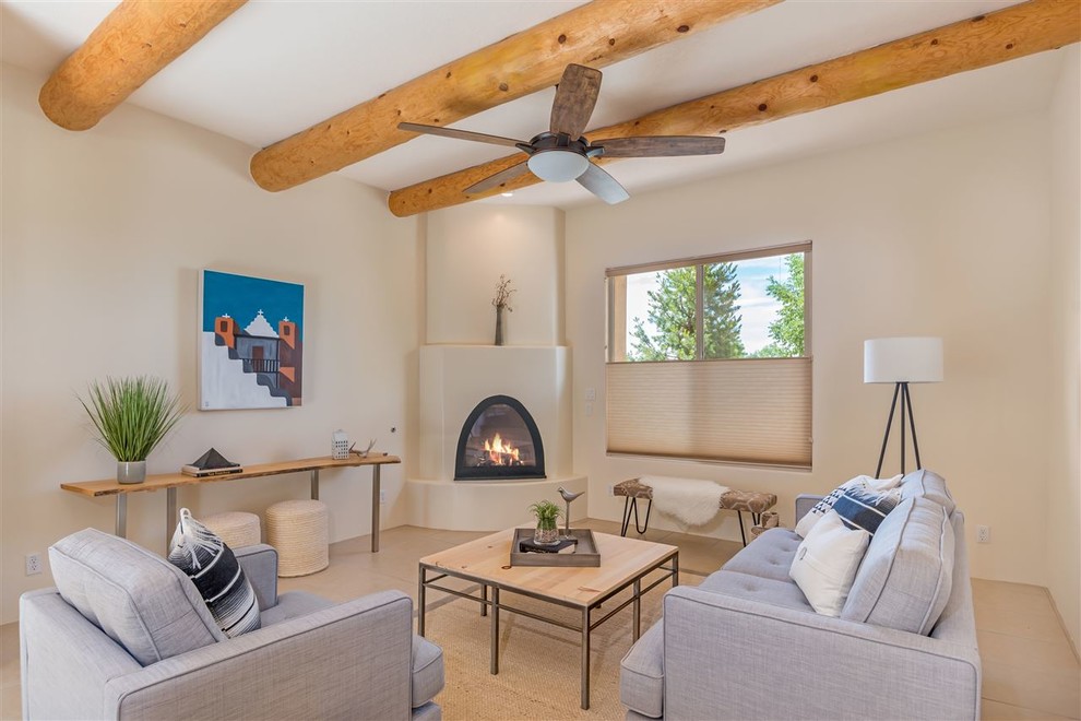 Living room - mid-sized southwestern open concept travertine floor and beige floor living room idea in Other with beige walls, a corner fireplace, a plaster fireplace and no tv