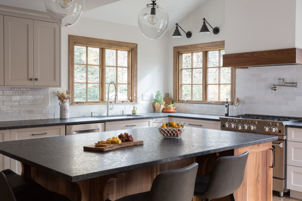 Exempel på ett stort klassiskt svart svart l-kök, med en undermonterad diskho, beige skåp, granitbänkskiva, vitt stänkskydd, stänkskydd i keramik, rostfria vitvaror, mellanmörkt trägolv, en köksö, brunt golv och luckor med infälld panel