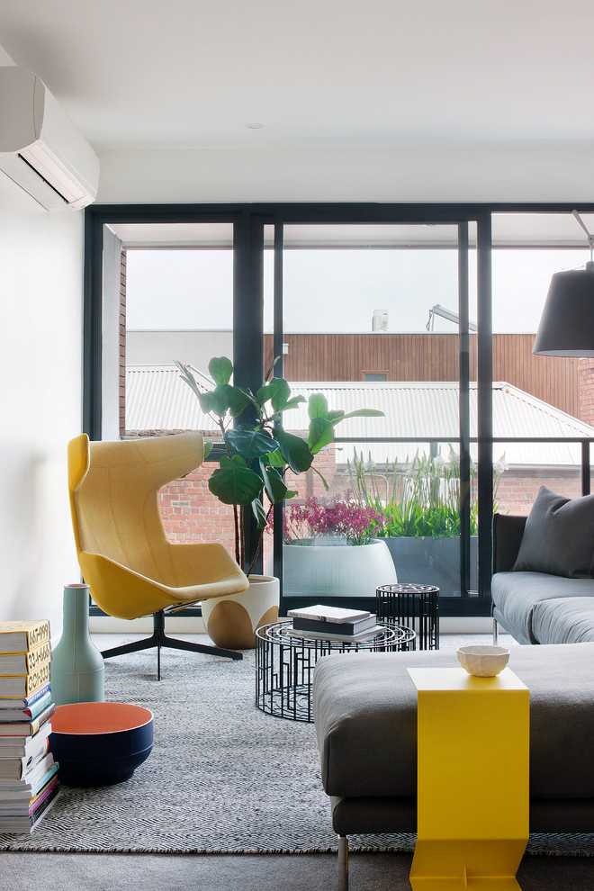 This is an example of a contemporary living room in Melbourne with white walls and carpet.