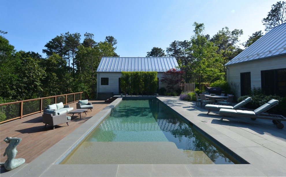 Photo of a mid-sized beach style courtyard rectangular lap pool in Boston with a water feature and concrete pavers.