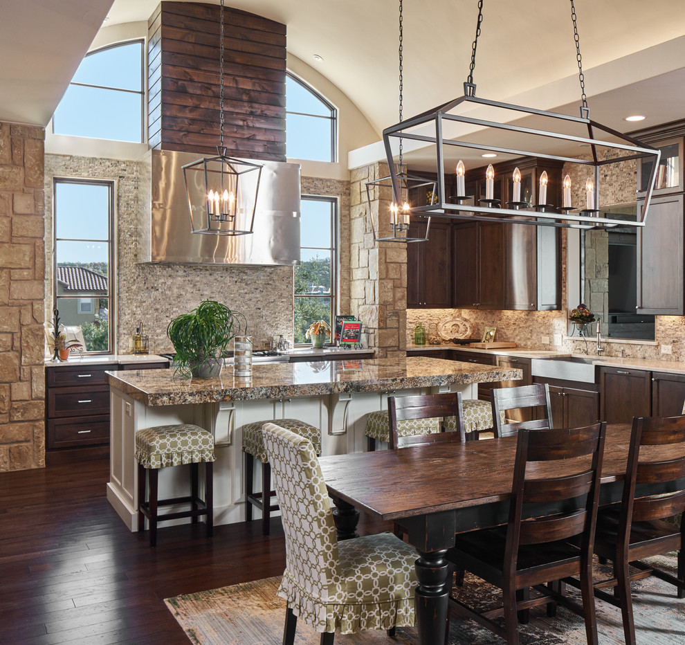 This is an example of a mid-sized transitional u-shaped eat-in kitchen in Austin with a farmhouse sink, shaker cabinets, dark wood cabinets, marble benchtops, beige splashback, stone tile splashback, stainless steel appliances, dark hardwood floors and with island.