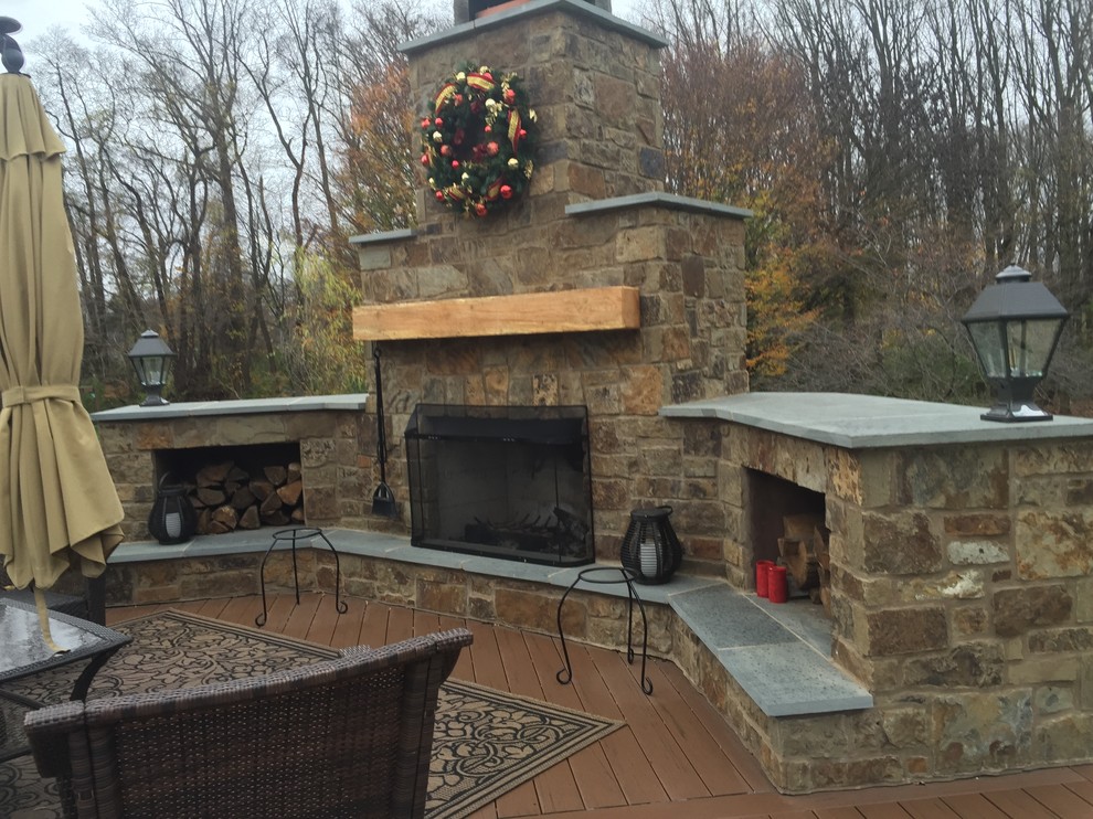 This is an example of a large traditional backyard deck in Philadelphia with with fireplace and a roof extension.