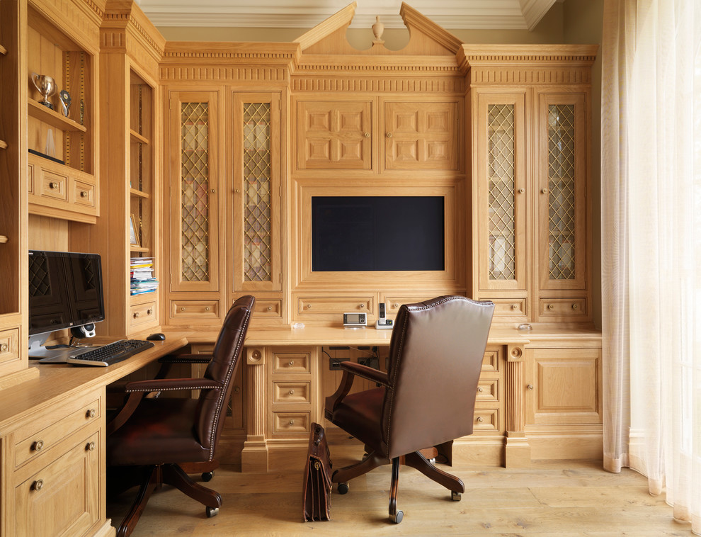 This is an example of a traditional study room in London with a built-in desk and medium hardwood floors.
