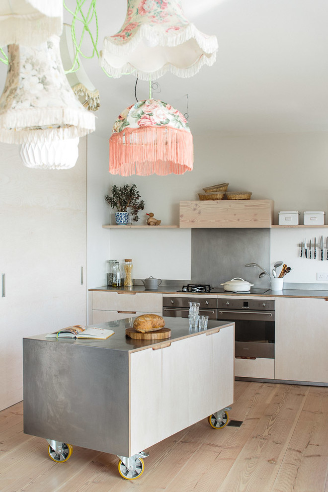 Mid-sized scandinavian l-shaped eat-in kitchen in Other with a farmhouse sink, flat-panel cabinets, light wood cabinets, stainless steel benchtops, metallic splashback, stainless steel appliances, light hardwood floors and with island.