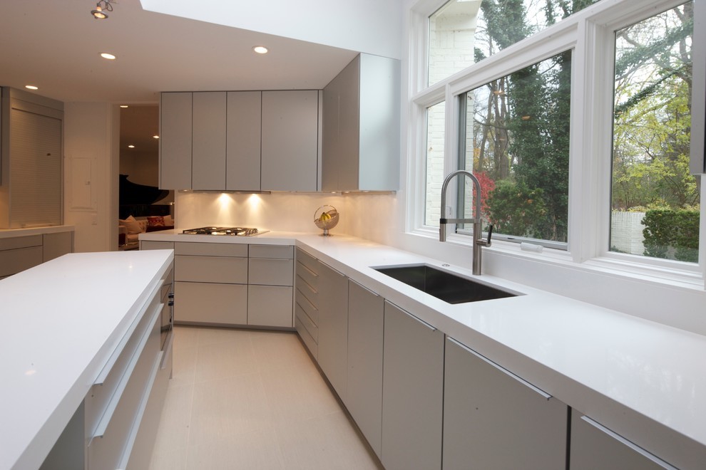Eat-in kitchen - mid-sized contemporary galley ceramic tile and beige floor eat-in kitchen idea in Detroit with an undermount sink, flat-panel cabinets, gray cabinets, solid surface countertops, white backsplash, ceramic backsplash, stainless steel appliances and an island