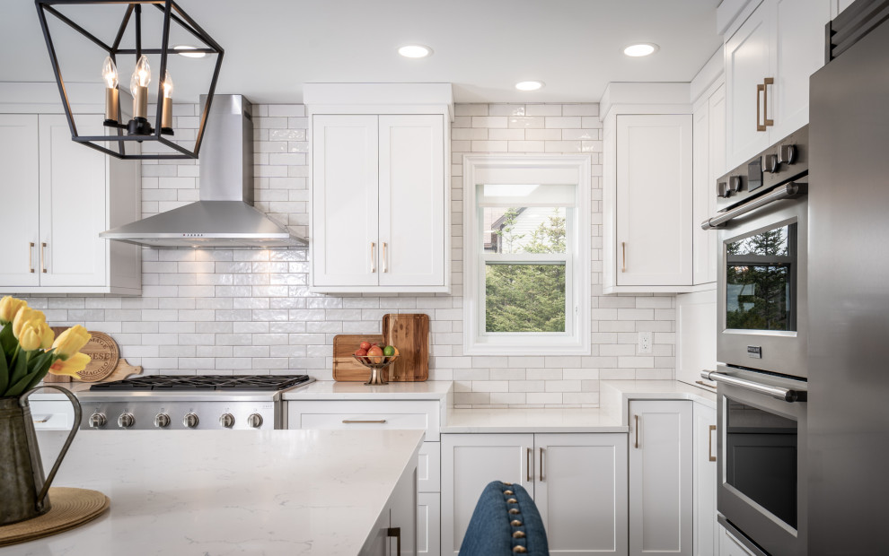 Example of a mid-sized transitional l-shaped ceramic tile and gray floor eat-in kitchen design with an undermount sink, white cabinets, quartz countertops, white backsplash, ceramic backsplash, stainless steel appliances, an island and white countertops