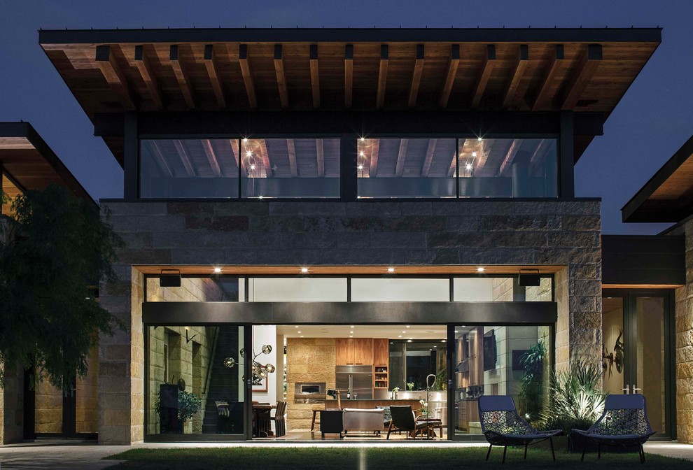 Inspiration for a large contemporary two-storey beige exterior in Austin with stone veneer and a flat roof.