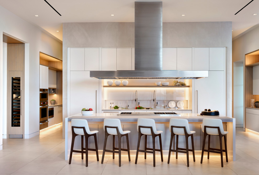 Immagine di una grande cucina design con ante lisce, ante bianche, paraspruzzi bianco, elettrodomestici in acciaio inossidabile, pavimento beige e top beige