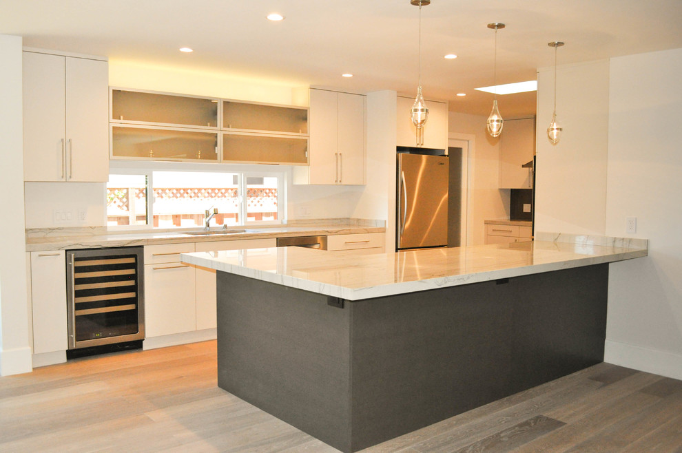 Contemporary u-shaped eat-in kitchen in San Francisco with an undermount sink, flat-panel cabinets, white cabinets, granite benchtops and stainless steel appliances.