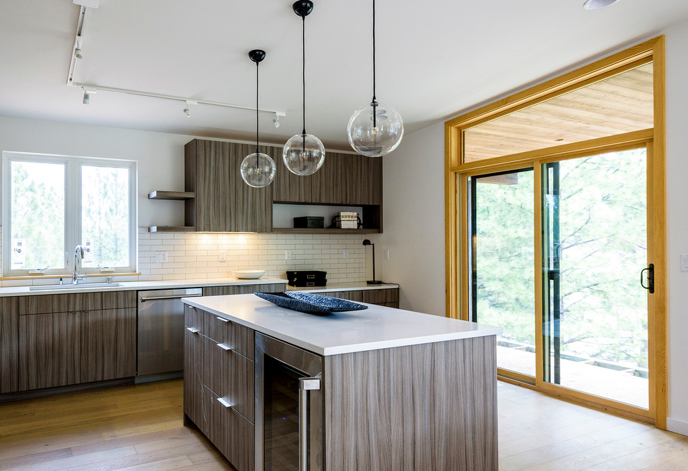 This is an example of a mid-sized modern l-shaped open plan kitchen in Other with an undermount sink, flat-panel cabinets, grey cabinets, quartz benchtops, white splashback, porcelain splashback, stainless steel appliances, medium hardwood floors, with island, brown floor and white benchtop.