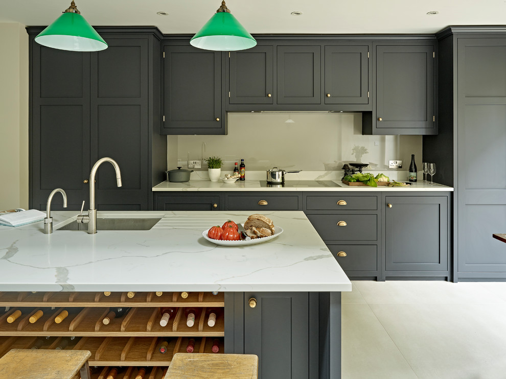 This is an example of a large traditional kitchen/diner in London with shaker cabinets, black cabinets, composite countertops, grey splashback, porcelain flooring, an island and grey floors.