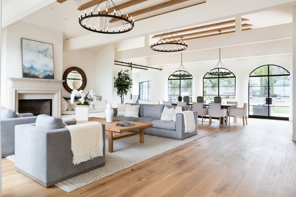 Inspiration for a country formal open concept living room in Los Angeles with white walls, light hardwood floors, a standard fireplace, a stone fireplace surround, no tv and brown floor.