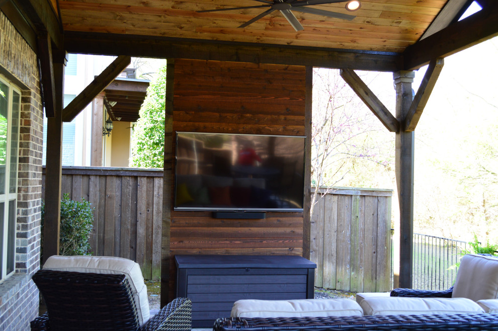 Exemple d'un grand porche d'entrée de maison arrière éclectique avec du béton estampé et une pergola.