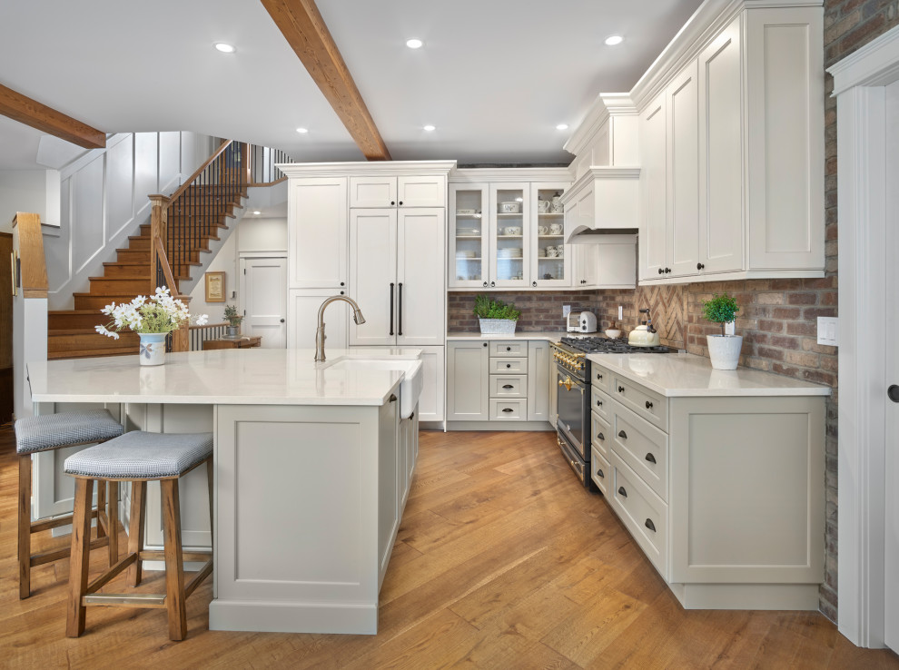 Design ideas for a l-shaped kitchen in Edmonton with a farmhouse sink, shaker cabinets, grey cabinets, brown splashback, brick splashback, panelled appliances, medium hardwood floors, with island, brown floor, white benchtop and exposed beam.