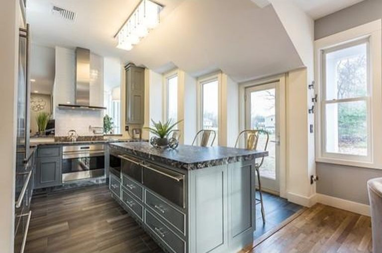 This is an example of a mid-sized contemporary l-shaped eat-in kitchen in Boston with a farmhouse sink, beaded inset cabinets, grey cabinets, granite benchtops, white splashback, ceramic splashback, stainless steel appliances, porcelain floors, with island, black floor and black benchtop.