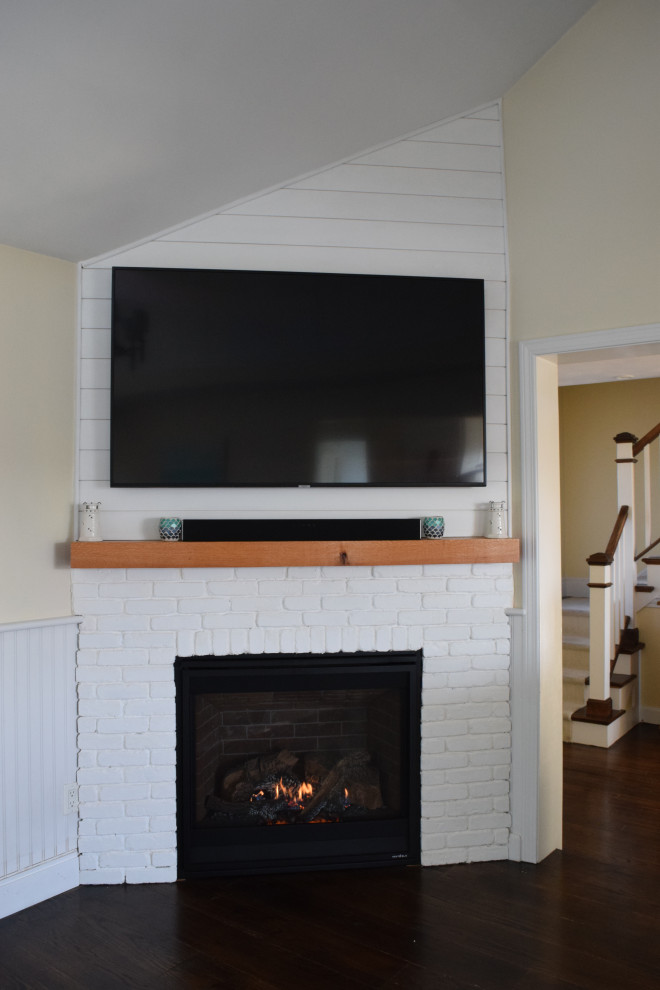 Photo of a mid-sized beach style open concept family room in Providence with white walls, dark hardwood floors, a corner fireplace, a brick fireplace surround, a built-in media wall, brown floor, vaulted and planked wall panelling.