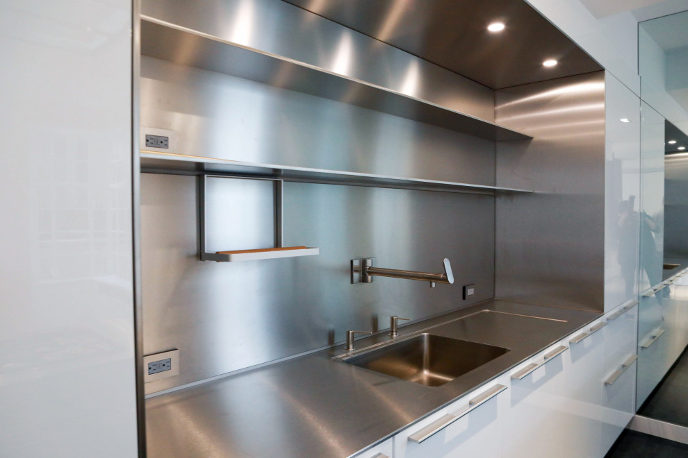 Inspiration for a large industrial galley eat-in kitchen in New York with an undermount sink, stainless steel cabinets, stainless steel benchtops, metallic splashback, stainless steel appliances, porcelain floors, multiple islands and grey floor.