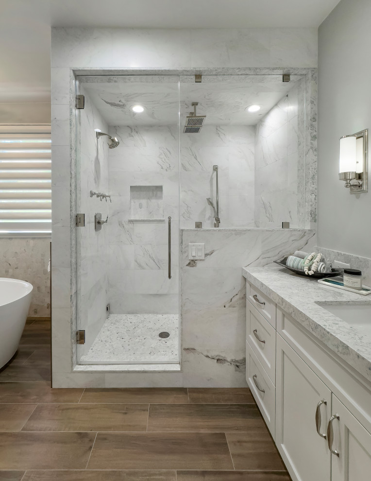 Inspiration for an expansive coastal ensuite bathroom in Orange County with shaker cabinets, a freestanding bath, a double shower, a one-piece toilet, marble tiles, a submerged sink, engineered stone worktops, an open shower, blue worktops, double sinks and a built in vanity unit.