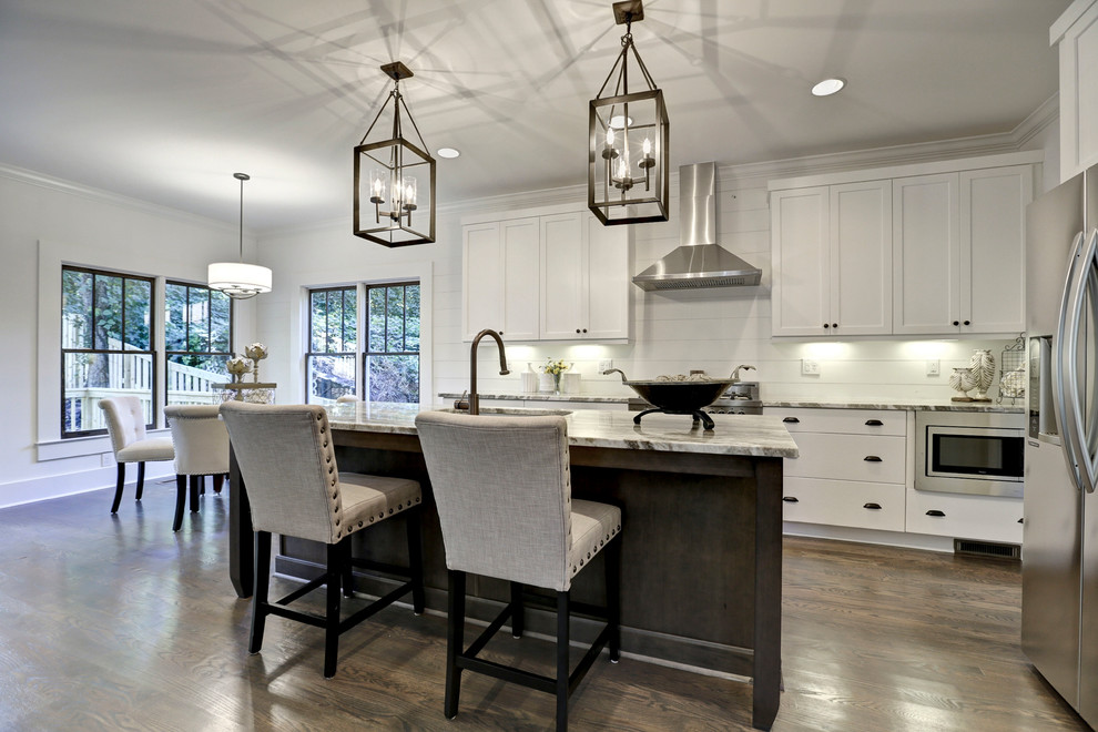 This is an example of a mid-sized transitional galley open plan kitchen in Atlanta with an undermount sink, shaker cabinets, white cabinets, quartzite benchtops, white splashback, stainless steel appliances, medium hardwood floors, with island and shiplap splashback.