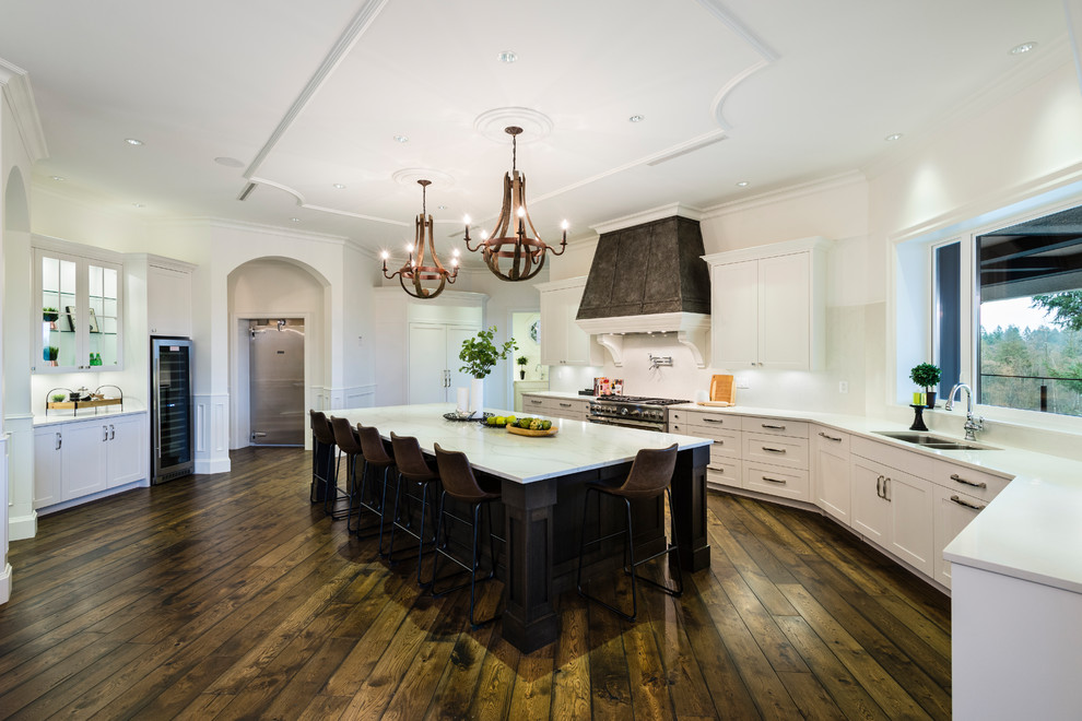 Inspiration for a huge rustic u-shaped medium tone wood floor and brown floor open concept kitchen remodel in Vancouver with an undermount sink, shaker cabinets, white cabinets, solid surface countertops, white backsplash, stone slab backsplash, stainless steel appliances, an island and white countertops