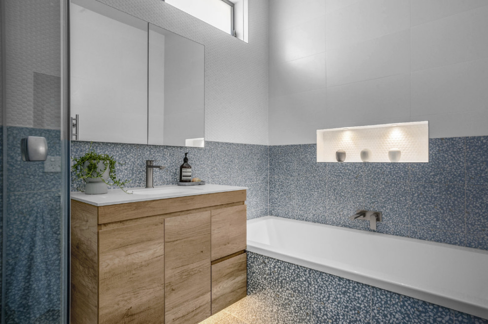Design ideas for a mid-sized modern bathroom in Melbourne with a floating vanity, a corner shower, terrazzo floors, an undermount sink, engineered quartz benchtops, blue floor, a hinged shower door, a niche, a single vanity, medium wood cabinets, a drop-in tub, porcelain tile and white benchtops.