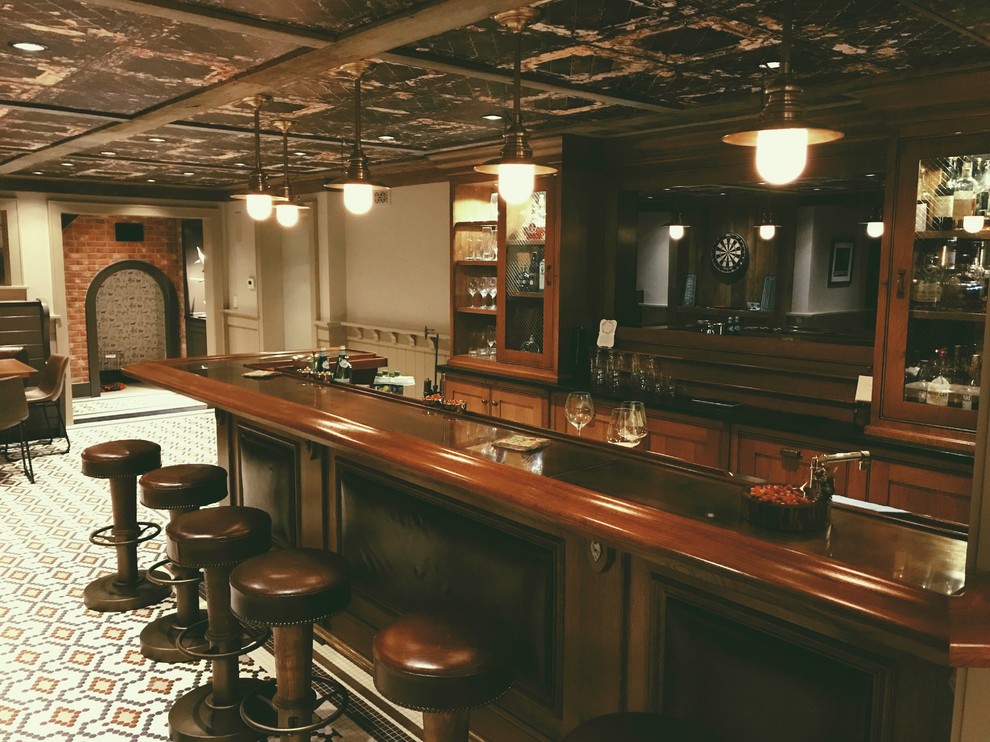 Traditional seated home bar in New York with shaker cabinets, dark wood cabinets and porcelain floors.
