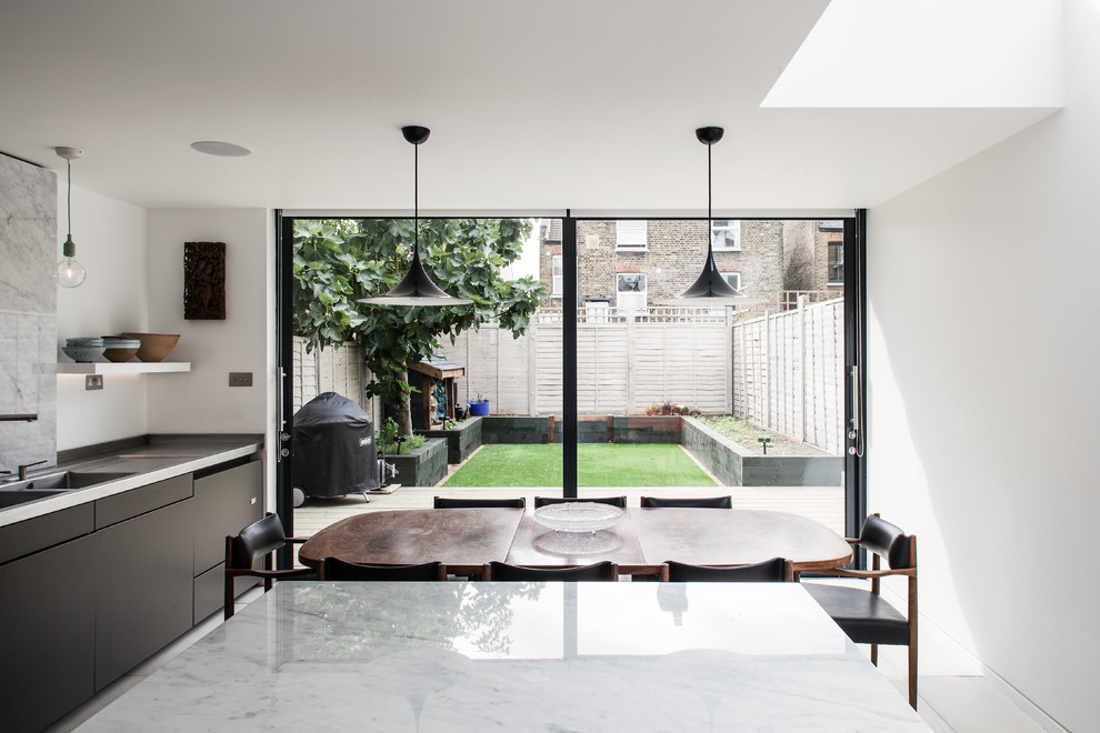 Design ideas for a contemporary eat-in kitchen in London with a double-bowl sink, flat-panel cabinets, grey cabinets and white splashback.