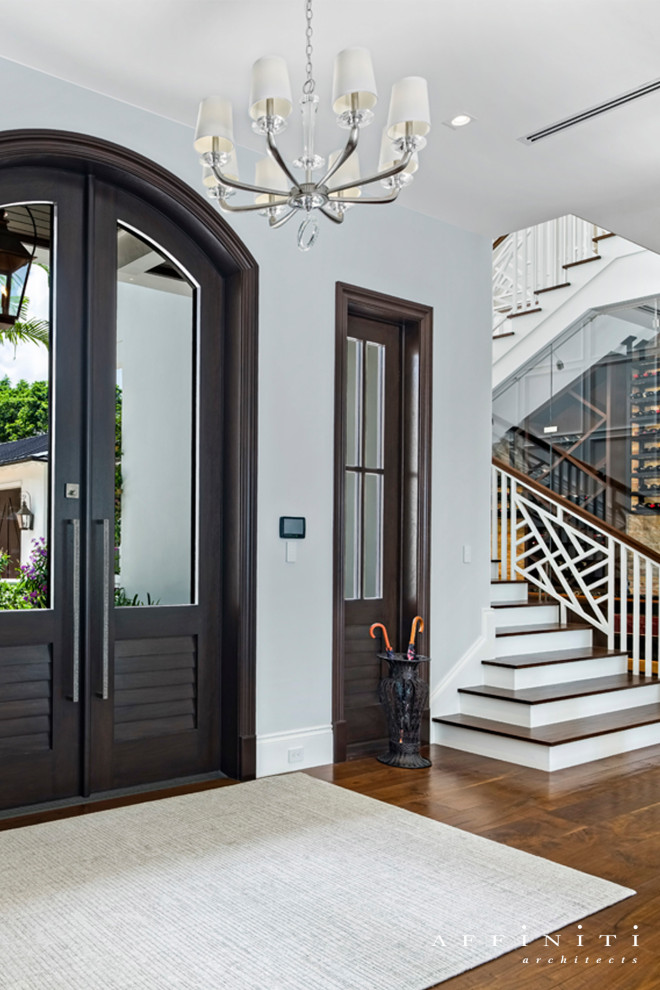 Example of a transitional medium tone wood floor and brown floor front door design with white walls and a dark wood front door