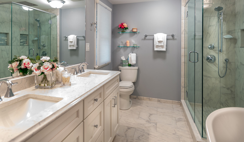 This is an example of a mid-sized eclectic master bathroom in Chicago with recessed-panel cabinets, white cabinets, a freestanding tub, a double shower, a two-piece toilet, multi-coloured tile, porcelain tile, grey walls, porcelain floors, an undermount sink, engineered quartz benchtops, multi-coloured floor, a hinged shower door and multi-coloured benchtops.