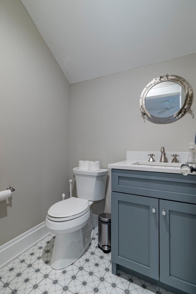 This is an example of a country cloakroom in Chicago with shaker cabinets, blue cabinets, a one-piece toilet, grey walls, ceramic flooring, a submerged sink, marble worktops, multi-coloured floors, white worktops, a freestanding vanity unit, a vaulted ceiling and wainscoting.