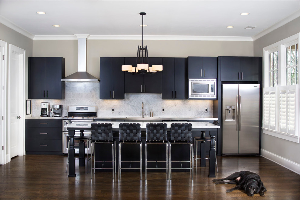 Transitional kitchen in Atlanta with flat-panel cabinets, black cabinets, grey splashback, stainless steel appliances, dark hardwood floors and with island.