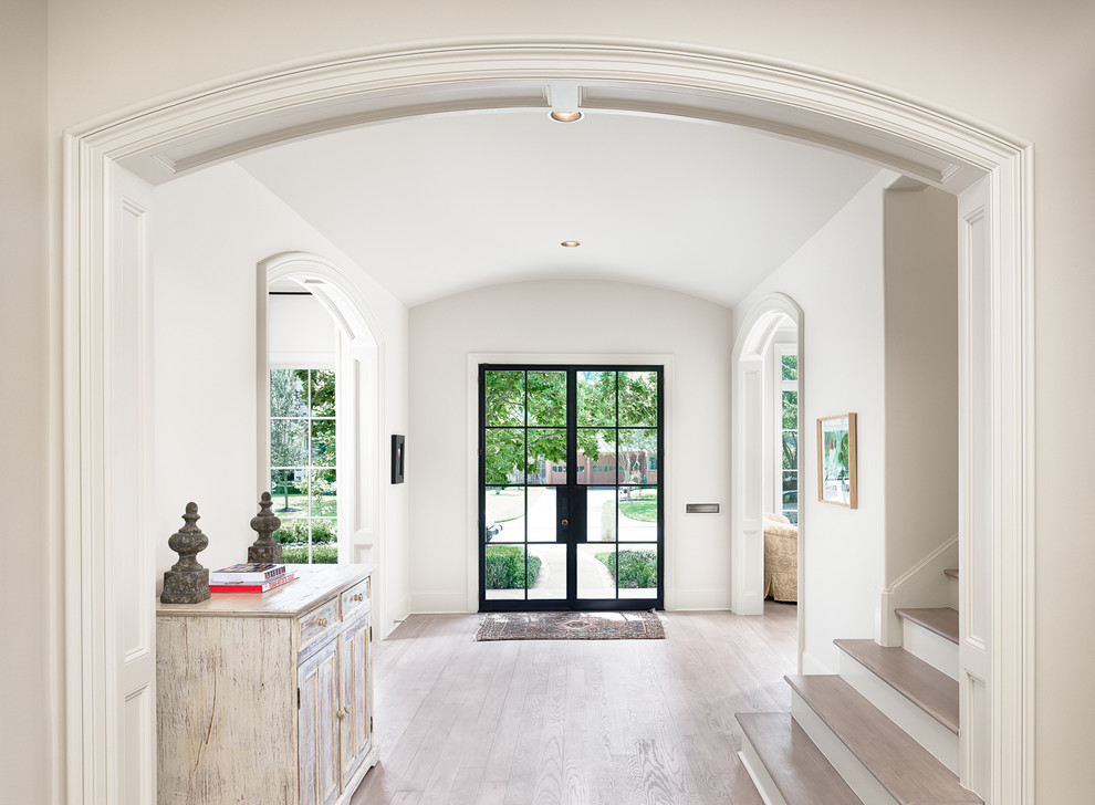 This is an example of a large country foyer in Houston with a double front door, a glass front door, white walls, light hardwood floors and beige floor.