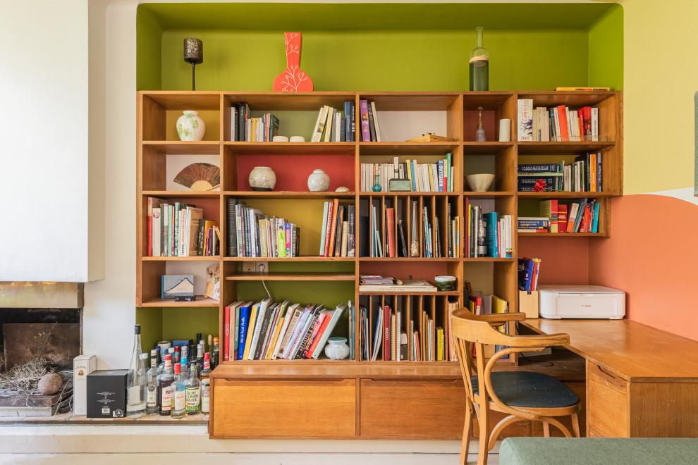 Inspiration for a mid-sized midcentury home office in Paris with a library, green walls, a standard fireplace, a built-in desk and beige floor.