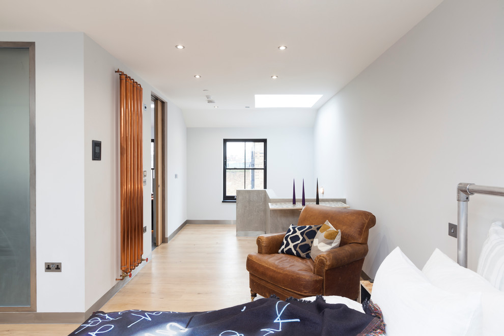Large contemporary loft-style bedroom in London with white walls, light hardwood floors and no fireplace.