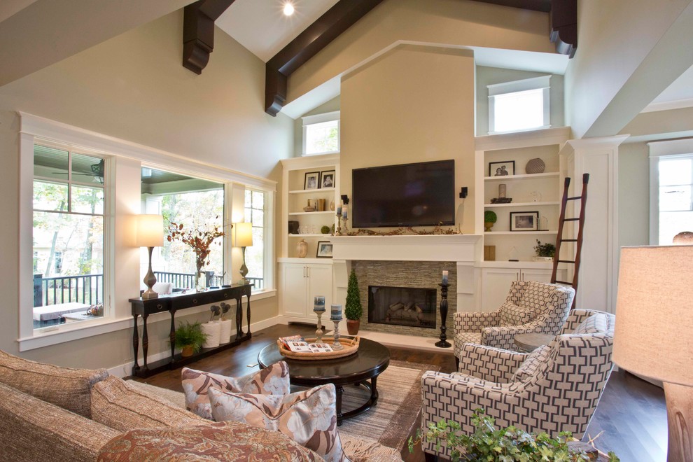 Design ideas for a traditional open concept living room in Grand Rapids with beige walls, dark hardwood floors, a standard fireplace, a stone fireplace surround, a wall-mounted tv and brown floor.