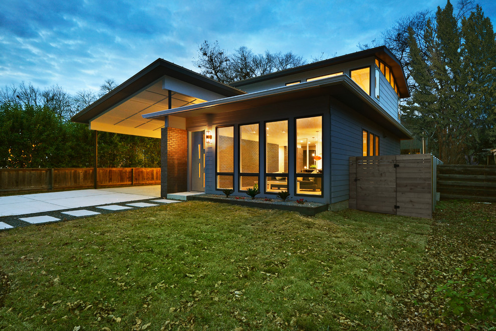 Mid-sized midcentury two-storey grey exterior in Austin with wood siding and a gable roof.