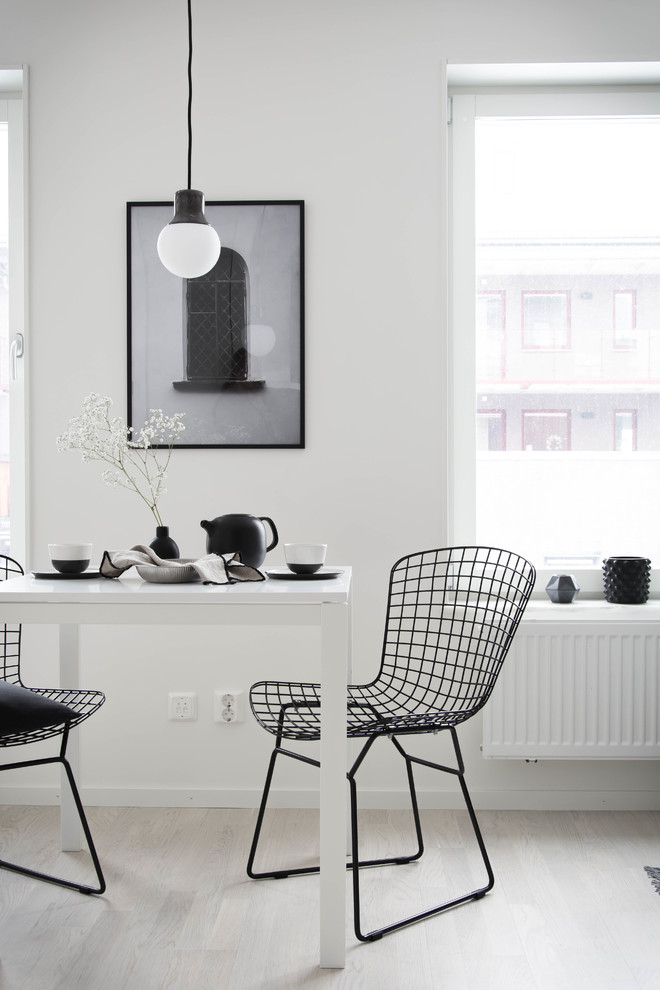 Small scandinavian dining room in Orebro with white walls, light hardwood floors and no fireplace.