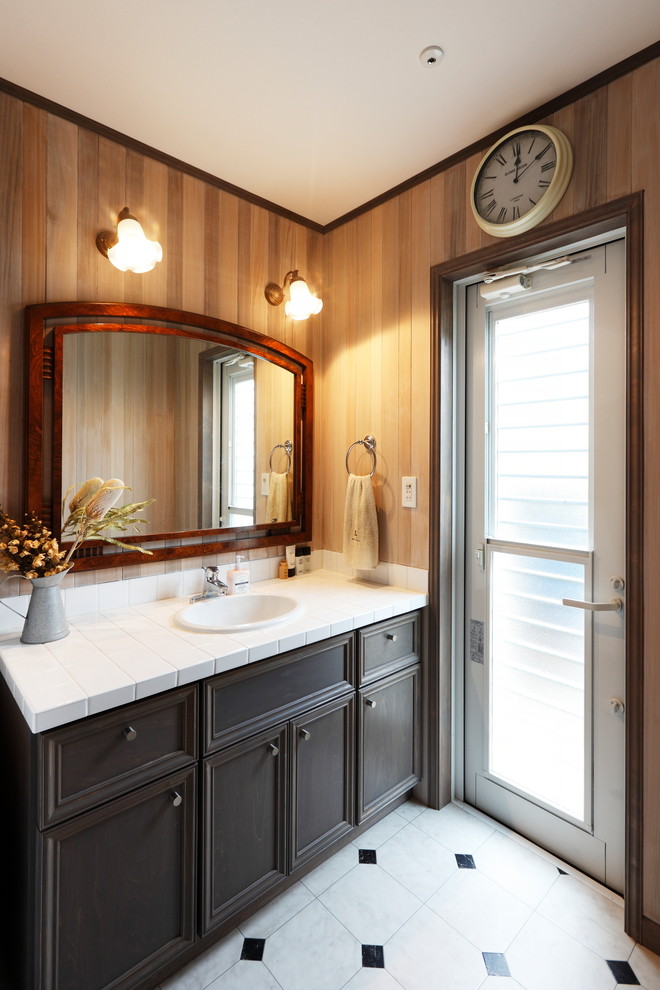 Midcentury powder room in Other with recessed-panel cabinets, black cabinets, brown walls, a drop-in sink and tile benchtops.