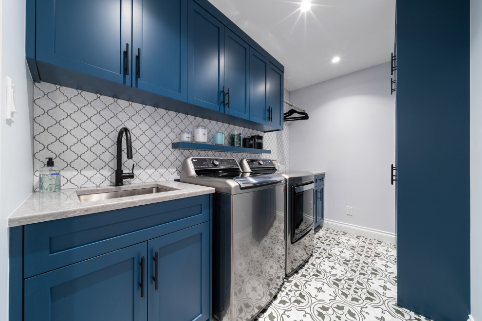 Design ideas for a large contemporary dedicated laundry room in Vancouver with an undermount sink, shaker cabinets, blue cabinets, quartz benchtops, white splashback, ceramic splashback, grey walls, porcelain floors, a side-by-side washer and dryer, grey floor and grey benchtop.