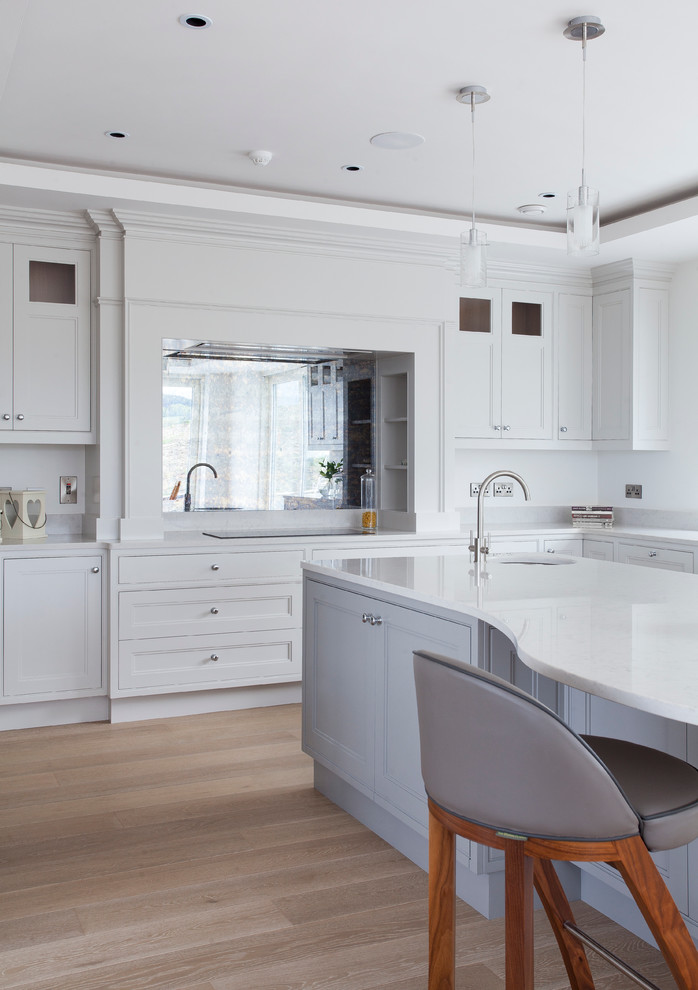 Photo of a contemporary u-shaped eat-in kitchen in Dublin with a double-bowl sink, beaded inset cabinets, quartz benchtops, mirror splashback, stainless steel appliances, medium hardwood floors and with island.