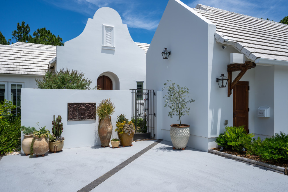Cette photo montre une grande façade de maison blanche bord de mer en stuc de plain-pied avec un toit mixte et un toit blanc.
