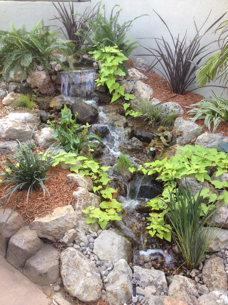Photo of a country backyard partial sun garden in Los Angeles with with pond and natural stone pavers.