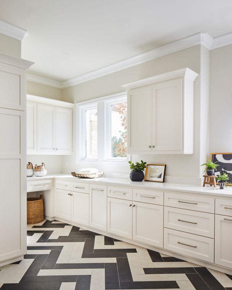 Inspiration for a large transitional l-shaped dedicated laundry room in Other with an undermount sink, shaker cabinets, white cabinets, solid surface benchtops, white splashback, stone slab splashback, white walls, porcelain floors, a side-by-side washer and dryer, white floor and white benchtop.
