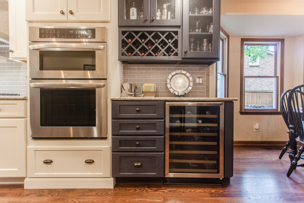 Example of a large transitional single-wall dark wood floor, brown floor and coffered ceiling eat-in kitchen design in Cincinnati with a double-bowl sink, shaker cabinets, white cabinets, granite countertops, gray backsplash, subway tile backsplash, stainless steel appliances, an island and multicolored countertops