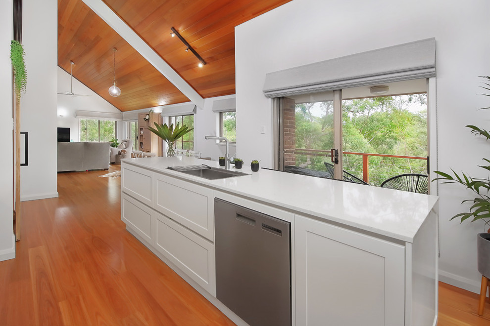 This is an example of a large modern single-wall open plan kitchen in Sydney with recessed-panel cabinets, yellow cabinets, quartz benchtops, white splashback, with island and white benchtop.