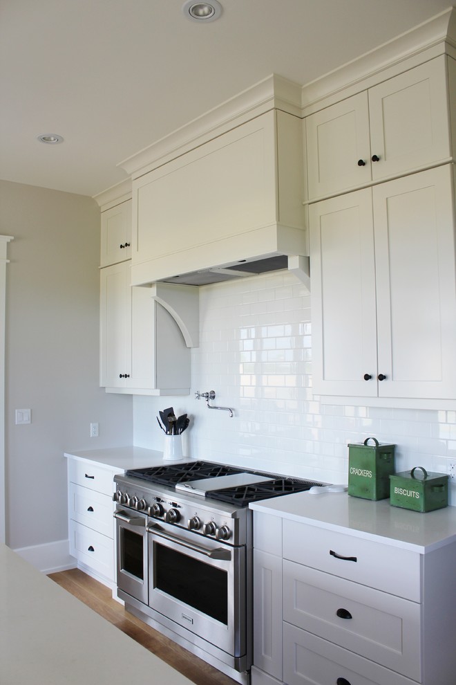 Eat-in kitchen - large transitional l-shaped eat-in kitchen idea in Toronto with an undermount sink, shaker cabinets, white cabinets, quartz countertops, white backsplash, stainless steel appliances and an island