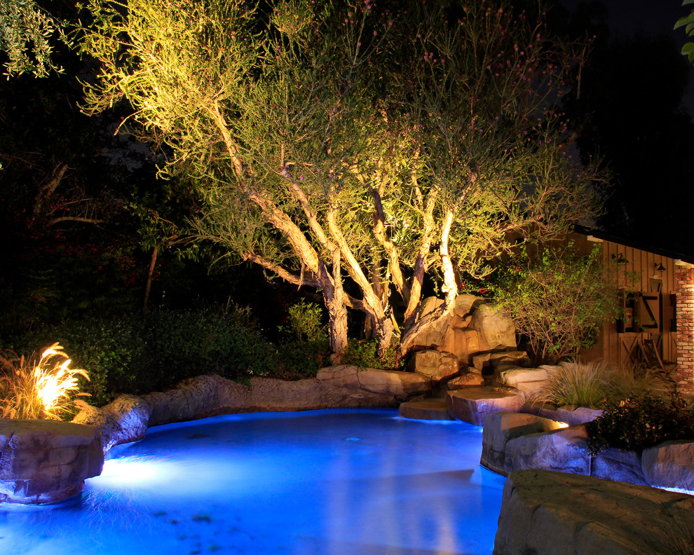 Inspiration for a mid-sized country backyard custom-shaped lap pool in Orange County with a hot tub and natural stone pavers.
