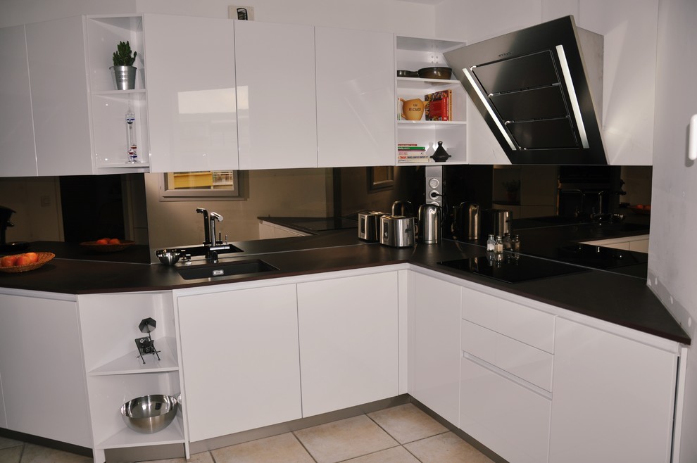 Mid-sized contemporary l-shaped separate kitchen in Montpellier with an integrated sink, white cabinets, grey splashback, mirror splashback, stainless steel appliances, ceramic floors and no island.